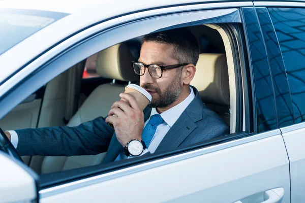在眼镜的商人的侧面视图与咖啡去驾驶汽车 — 图库照片