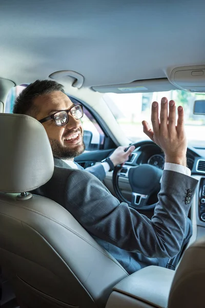 Biznesmen Uśmiechający Się Garnitur Okulary Powitanie Ktoś Podczas Jazdy Samochodem — Zdjęcie stockowe