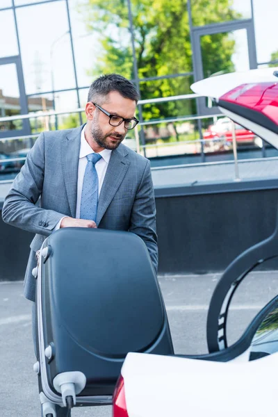 Portret Biznesmen Okularach Oddanie Bagażu Samochodu Parkingu — Darmowe zdjęcie stockowe