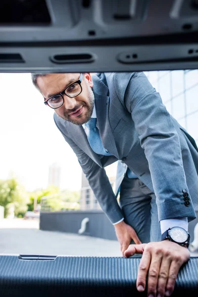 Geschäftsmann Anzug Und Brille Schaut Den Kofferraum — kostenloses Stockfoto