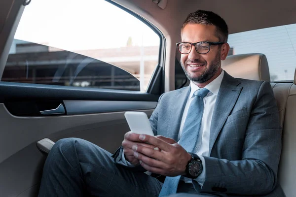 Χαμογελώντας Επιχειρηματίας Χρησιμοποιώντας Smartphone Στο Πίσω Κάθισμα Στο Αυτοκίνητο — Φωτογραφία Αρχείου