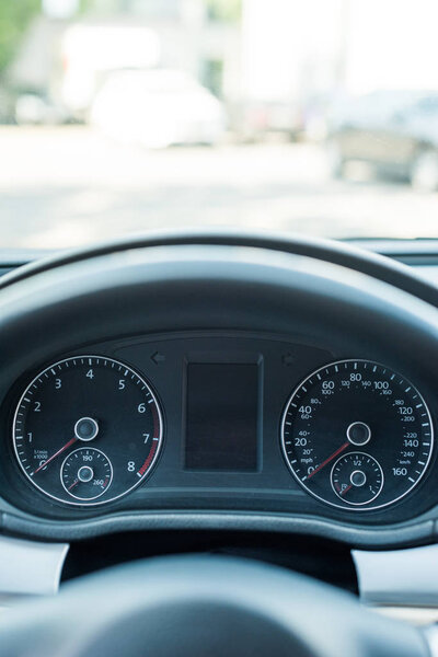 close up view of black speedometer and steering wheel in car