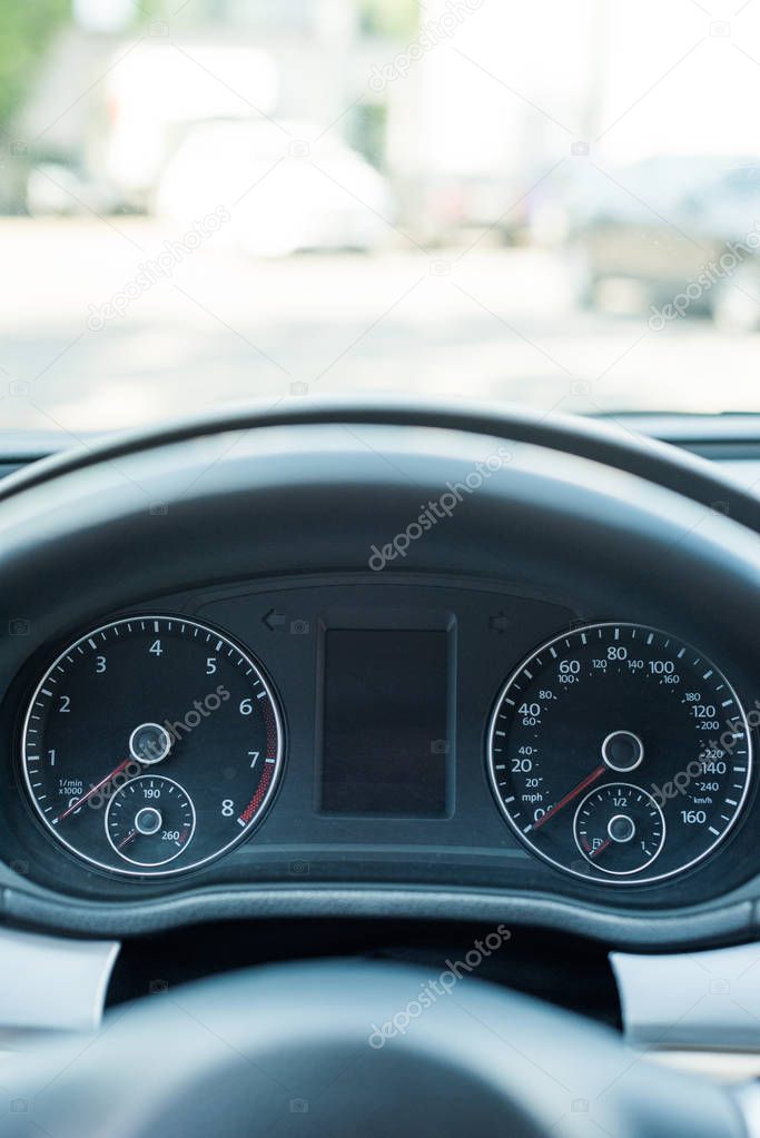 close up view of black speedometer and steering wheel in car