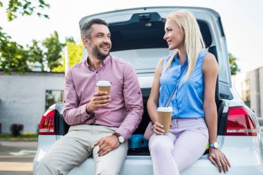 Gidip arabanın üzerine oturan birbirine bakarak kahve ile çift gülümseyen portresi