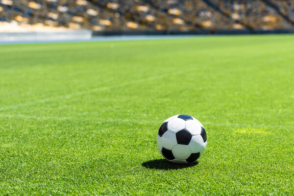 soccer ball lying on green grass of stadium