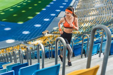 high angle view of beautiful athletic woman jogging upstairs at sports stadium clipart