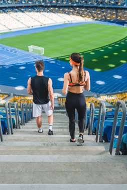 high angle view of young fit couple walking downstairs at sports stadium clipart