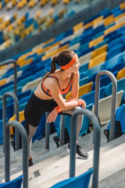 spor stadyumunda merdivenlerde yorgun sportif kadının rahatlatıcı yüksek açılı görünüş