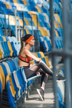 çekici genç kadın tribün spor stadyumunda otururken yan görünüm