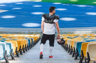 Genç Amerikan futbolu oyuncusu spor stadyumunda merdivenlerde dikiz