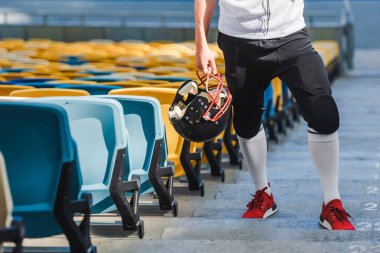 Amerikan futbolu oyuncusu kask ayakta merdivenlerde spor stadyum ile kadeh kırpılmış