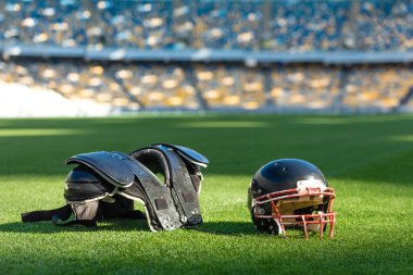 american football helmet with chest protection lying on green grass of stadium clipart