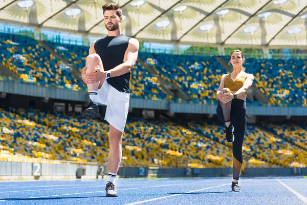 年轻的运动夫妇热身腿前慢跑跑道上体育场馆 — 图库照片