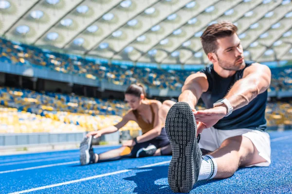 Jovem Casal Atlético Sentado Pista Corrida Alongamento Estádio Esportes — Fotografia de Stock