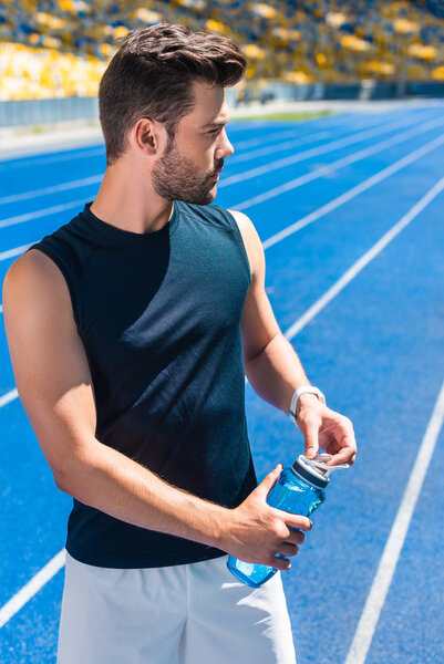 attractive young man with water bottle at sports stadium