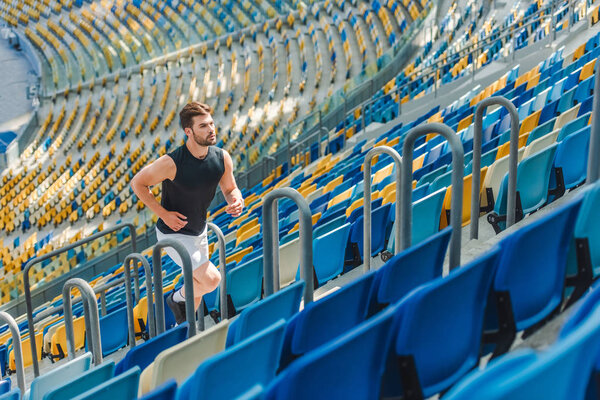 fit young man jogging upstairs at sports stadium