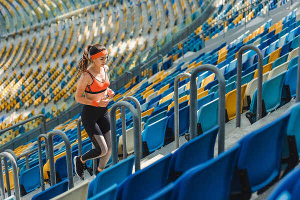 high angle view of beautiful fit woman jogging upstairs at sports stadium