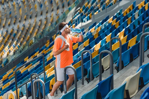 疲惫的年轻运动员在体育场的楼梯上喝水 — 免费的图库照片