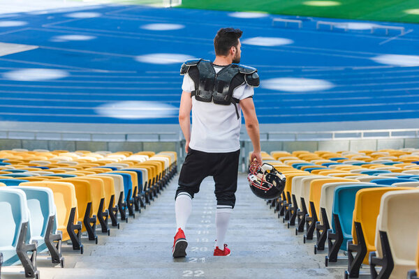 rear view of young american football player on stairs at sports stadium