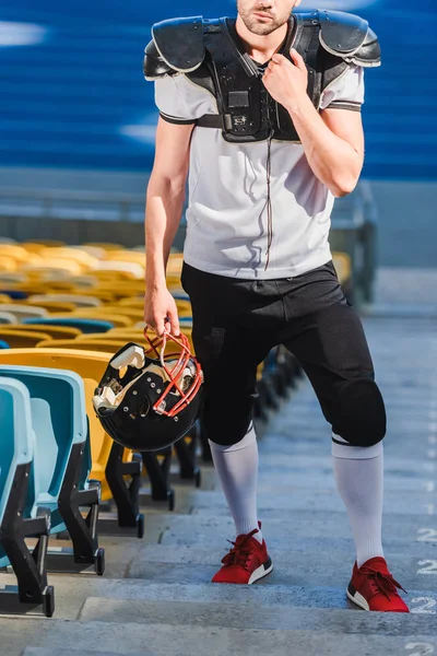 スポーツ スタジアムの階段の上に立ってハンサムな若いアメリカン フットボール プレーヤーのクロップ撮影  — 無料ストックフォト