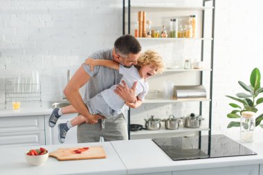 baba holding gülen oğul ve onu mutfağa gıdıklıyor