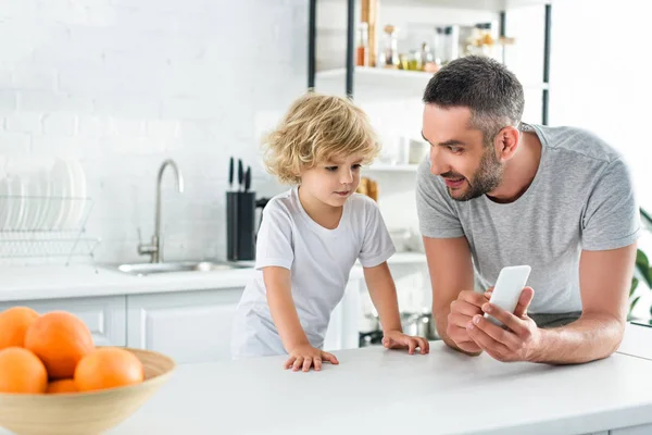 Souriant Père Montrant Smartphone Petit Fils Cuisine — Photo