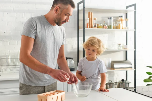 卵とキッチンで生地の準備をする泡立て器で息子と父  — 無料ストックフォト