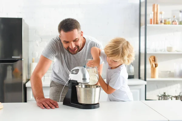 Liten Pojke Hälla Mjöl Mixer Skål Medan Hans Far Som — Stockfoto