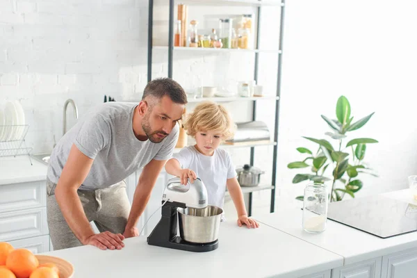 Pai Assistindo Como Seu Filho Usando Misturador Para Fazer Massa — Fotografia de Stock