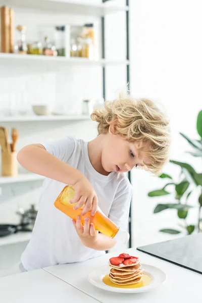 Menino Derramando Xarope Panquecas Com Pedaços Morango Placa Cozinha — Fotografia de Stock