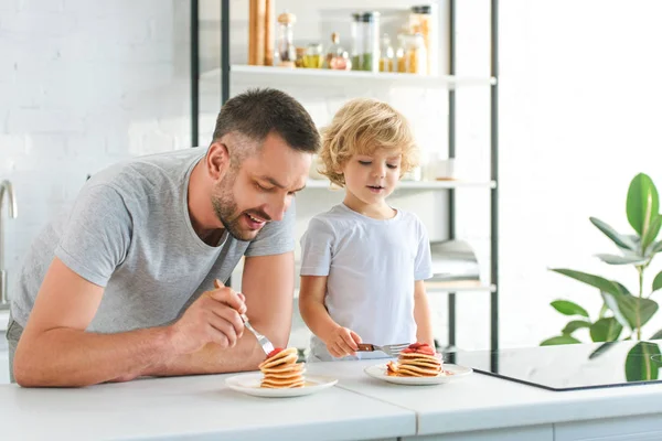 幸せな父と息子がキッチンでパンケーキを食べて — ストック写真