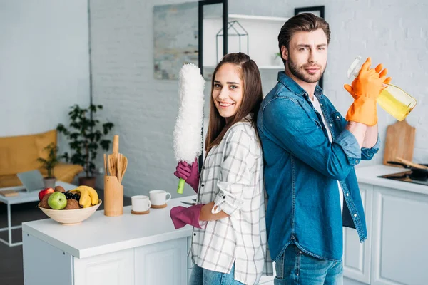 couple having fun during cleaning kitchen and looking at camera