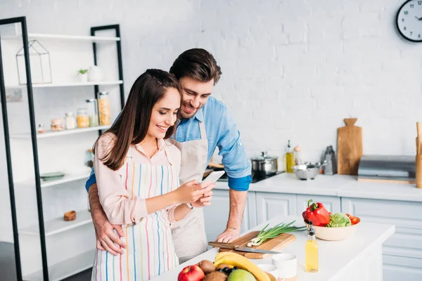 Paar Umarmt Sich Und Schaut Beim Kochen Küche Aufs Smartphone — Stockfoto