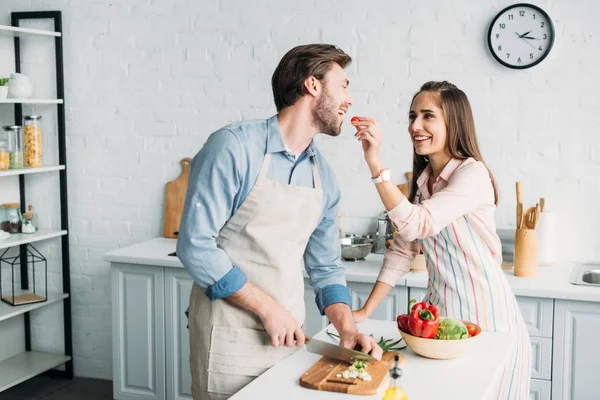 Boyfriend Cutting Vegetables Girlfriend Feeding Him Tomato Kitchen — Stock Photo, Image