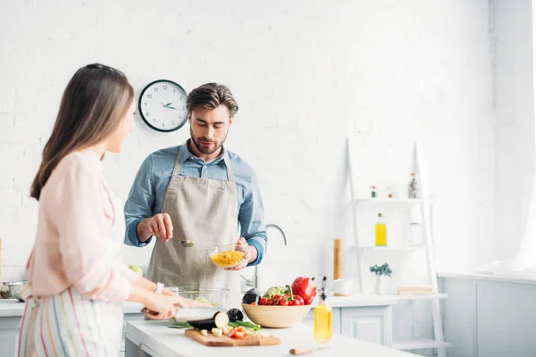 女朋友切菜和男朋友在厨房里加入玉米沙拉 — 图库照片