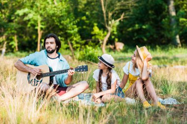 piknikte kızı ve karısı için akustik gitar çalmak baba
