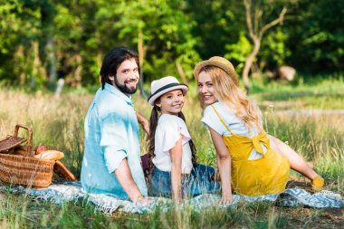 Anne ve kızı battaniye piknik ve kameraya bakarak otururken