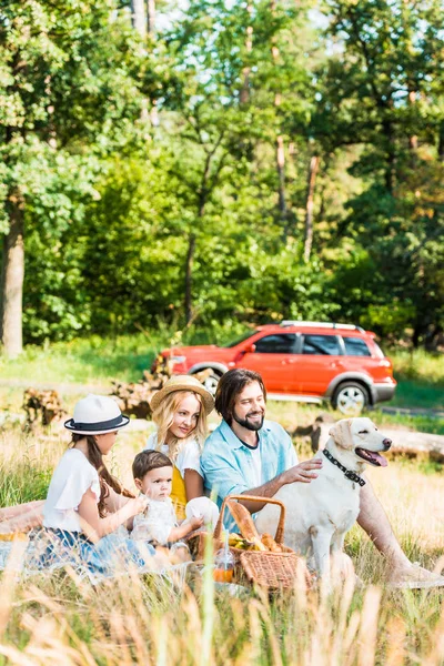 ラブラドール犬とのピクニックで時間を過ごす幸せな親子 — ストック写真