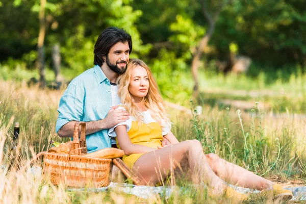 愛情のこもったカップルを抱き締めるとピクニックで草の上に座って — ストック写真