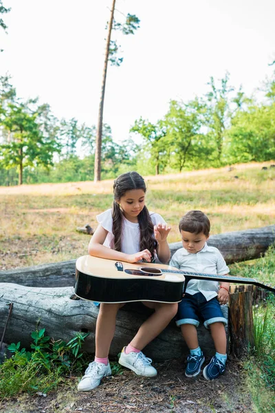 Bror Och Syster Sitter Loggen Gräsmattan Med Akustisk Gitarr — Gratis stockfoto