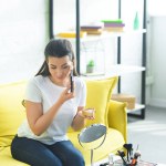 Retrato de mulher atraente aplicando blush rosto enquanto fazendo maquiagem em casa