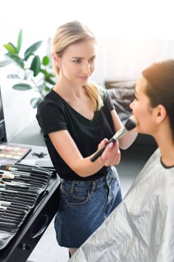 seçici odak fırça ile kadının yüzündeki tozu uygulama makyaj sanatçısı