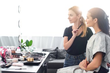 makyöz makyaj fırça ve güzel genç kadın yan görünüm aynaya bakarak bezle kaplı