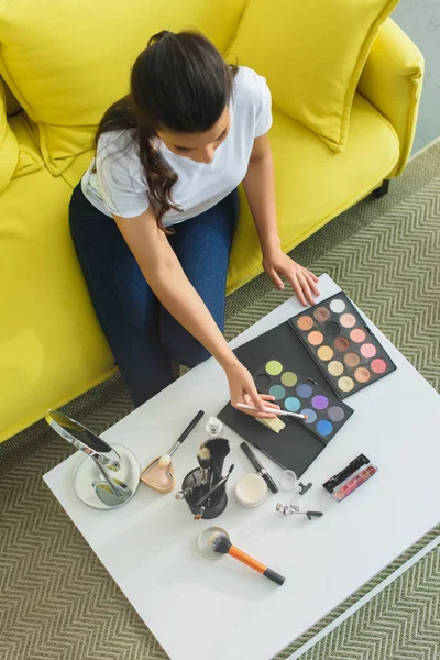 Vista Aérea Mujer Con Cepillo Maquillaje Sentado Sofá Mesa Café — Foto de stock gratis