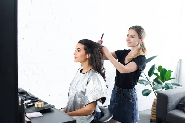 发型师用梳子做发型的侧面视图年轻妇女 — 图库照片