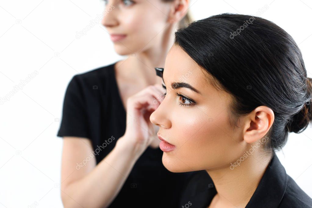 selective focus of young businesswoman getting makeup done by makeup artist
