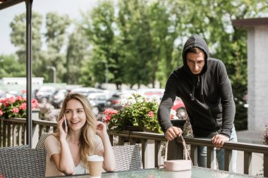 restoranın terasında kadın Smartphone'da söz ederken masaya çantasından hırsızlık suç adam