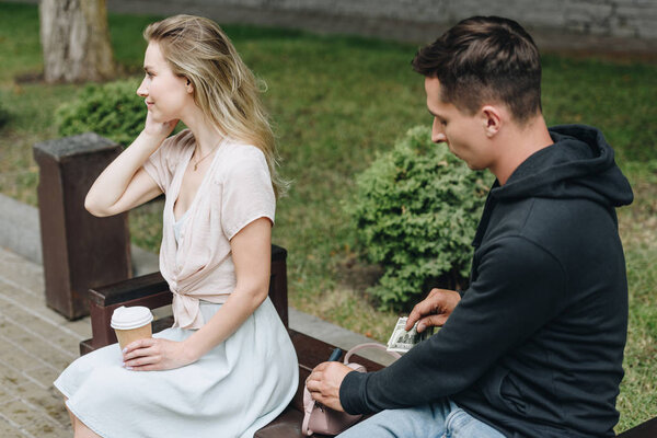 robbery pickpocketing money from purse while woman with coffee talking on smartphone and looking away in park  