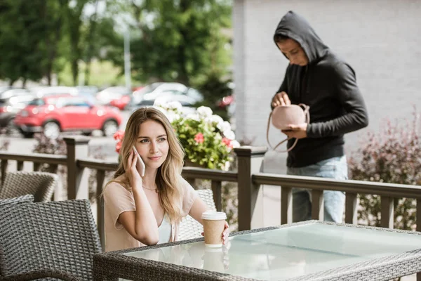 Man Stjäl Väska Från Tabellen Restaurangterrassen Medan Kvinnan Talar Smartphone — Stockfoto