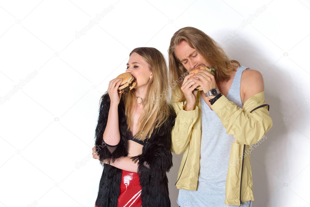 hungry young couple eating tasty burgers on white